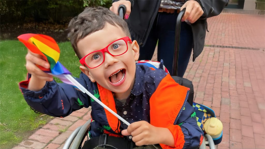 Cashen smiling while using his lightweight pediatric wheelchair.